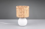 Lampa stołowa Vina z białą podstawą w kształcie kuli oraz kloszem z naturalnego włókna. Klosz ma okrągły kształt i jest pleciony, co nadaje mu teksturowany wygląd. Produkt stoi na szarej powierzchni, z widocznym kablem zasilającym.