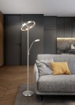 Lampa podłogowa Willis w kolorze niklowym, z dwoma źródłami światła LED. Posiada okrągłą górną część i elastyczne ramię, stojąca obok szarej sofy z poduszkami. Tło w odcieniach szarości i drewna, nowoczesne wnętrze.