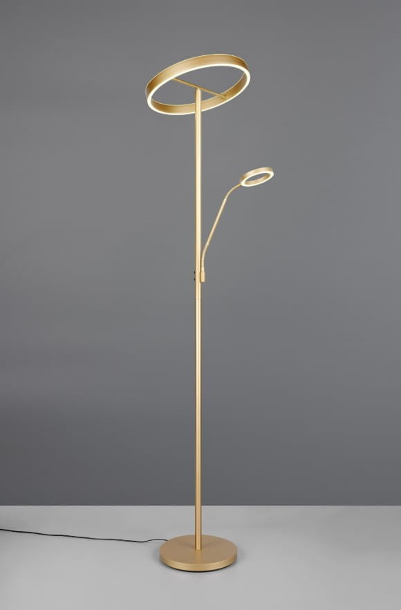 Lampa podłogowa Willis w kolorze złotym, z dwiema głowicami LED. Główna lampa ma okrągły kształt, a dodatkowa ramienna, umożliwiająca kierowanie światła. Ustawiona pionowo na okrągłej podstawie, z kablem zasilającym widocznym na podłodze.