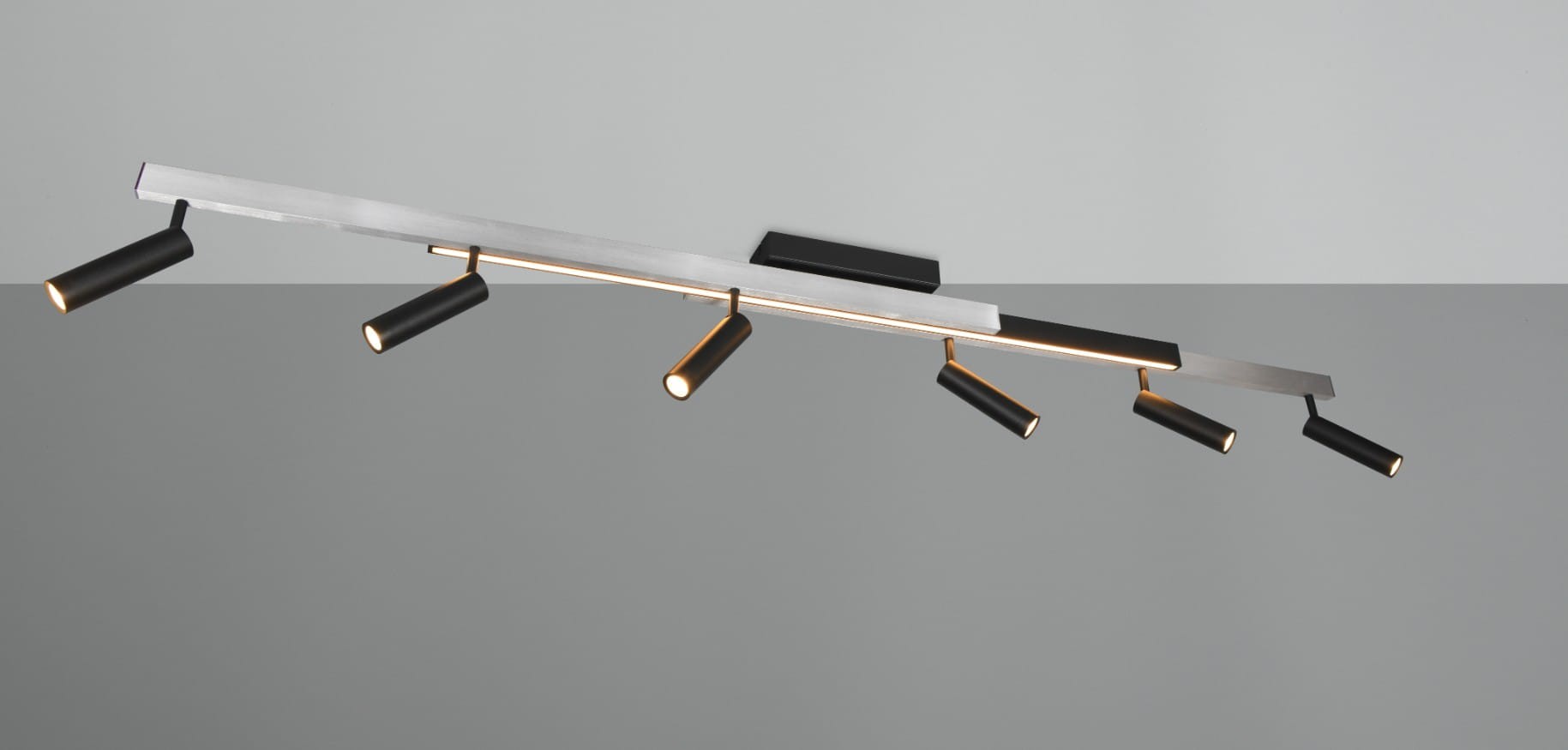 Lampa sufitowa Zeno w kolorze czarnym z aluminiowym wykończeniem, z siedmioma ruchomymi punktami świetlnymi. Ujęcie z boku, montowana na suficie, z pilotem do regulacji. Prosta, nowoczesna forma na szarym tle.