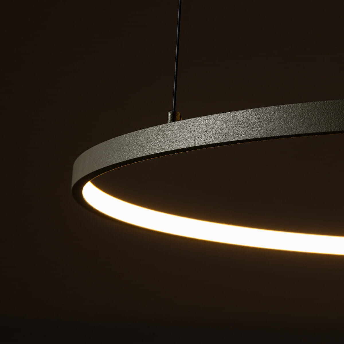 Lampa wisząca Circolo D60 w kolorze oliwkowym, z okrągłym, matowym kloszem, zawiera źródło światła LED o mocy 21W i temperaturze barwowej 3000K. Ujęcie zbliżone, pokazujące detal klosza i emitowane światło.