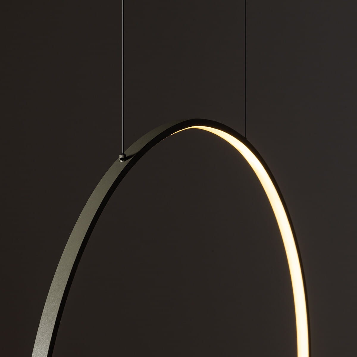 Lampa wisząca Circolo D60 w kolorze oliwkowym, z metalowym okręgiem. Źródło światła LED o mocy 21W i temperaturze barwowej 3000K. Produkt zawieszony na czarnych linkach, z widocznym delikatnym podświetleniem wewnętrznym.