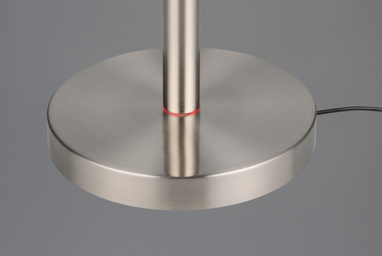 Lampa podłogowa Gomez w kolorze tytanowym z metalową podstawą i cienkim słupkiem. Widoczny czerwony element dekoracyjny na podstawie. Produkt jest w pozycji stojącej, z kablem zasilającym widocznym z boku.