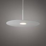 Lampa wisząca Simone 1xGX53 w kolorze białym, o okrągłym, płaskim kloszu zawieszonym na cienkim, metalowym pręcie. Źródło światła umieszczone w centralnej części klosza. Tło w odcieniu szarym, minimalistyczny design.