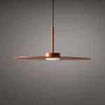 Lampa wisząca Simone w kolorze ceglanym z metalowym kloszem o okrągłym kształcie. Zamontowana na cienkim przewodzie, z centralnym źródłem światła wbudowanym w okrągłą podstawę. Ujęcie frontalne, na jednolitym tle.