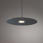 Niebieska lampa wisząca Simone z jednym źródłem światła GX53, w kształcie okrągłej, płaskiej tarczy, zawieszona na cienkim przewodzie. Elementy metalowe w matowym wykończeniu, w centralnej części widoczna żarówka. Tło w odcieniach szarości.