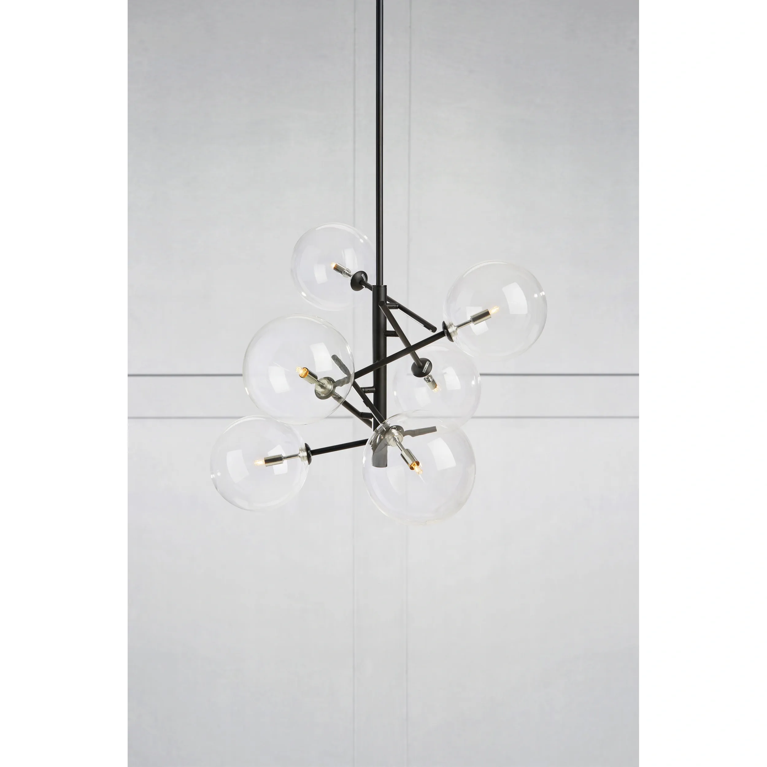 Lampa wisząca Andrew, 6-punktowa, w kolorze czarnym, z konstrukcją metalową. Szklane klosze w formie kul, rozmieszczone asymetrycznie. Produkt zawieszony na długim przewodzie, prezentujący nowoczesny design. Tło jasne, minimalistyczne.