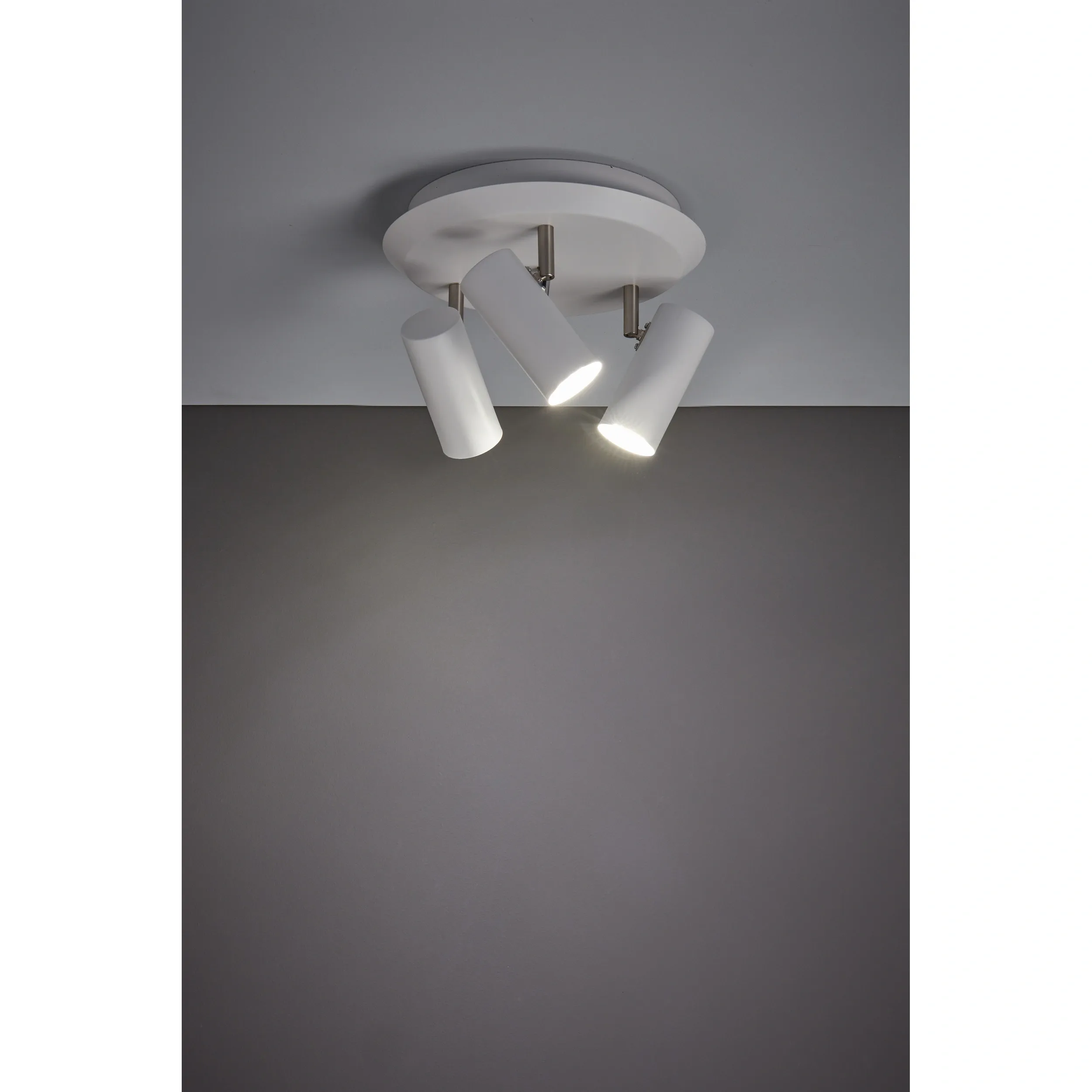 Lampa sufitowa Barcelona 3-punktowa w kolorze białym, z okrągłą podstawą i trzema cylindrycznymi reflektorami. Reflektory ustawione pod różnymi kątami, emitujące światło na szaro-białym tle.