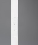 Biała lampa podłogowa Specter z jednym źródłem LED o mocy 17W. Zbliżenie na prostą, smukłą konstrukcję z widocznym panelem sterującym. Tło w odcieniu szarości.