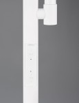 Biała lampa podłogowa Specter z dwoma źródłami LED (21,5W) z widocznym panelem sterującym na nodze. Ujęcie z boku, ukazujące detale przycisków oraz strukturę materiału. Proste, nowoczesne wzornictwo.