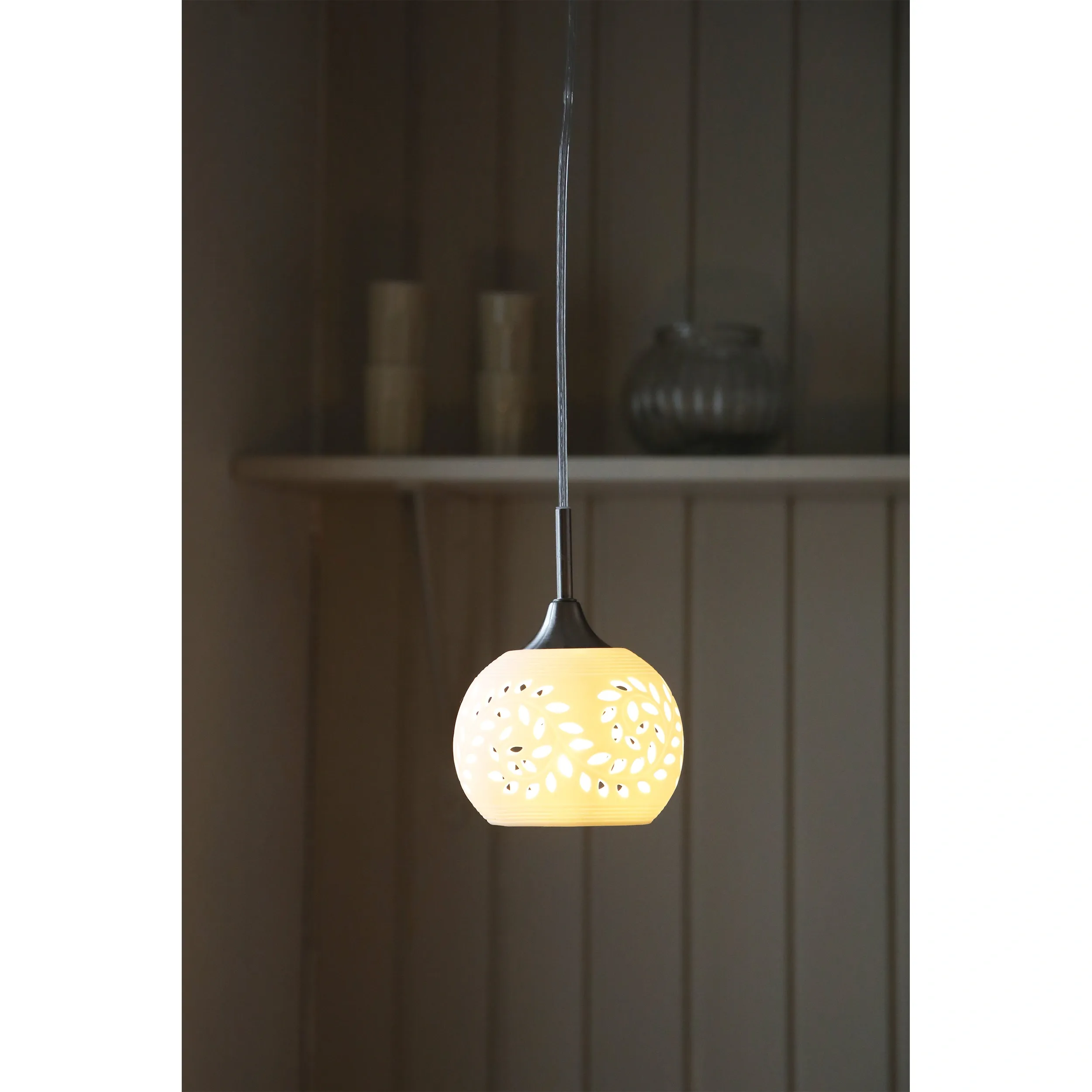 Lampa wisząca Lohals w kolorze białym, z metalowym wykończeniem, posiada okrągły klosz z delikatnym wzorem liści. Zawieszona na cienkim przewodzie, idealna do nowoczesnych wnętrz, w subtelnym, stonowanym otoczeniu.
