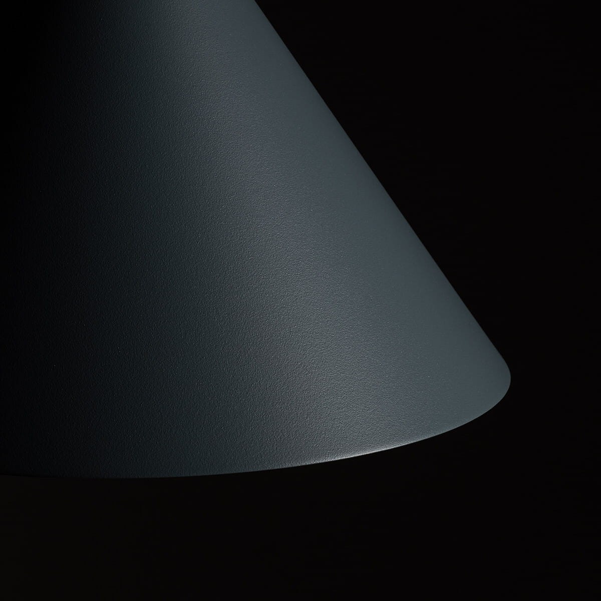 Niebieska lampa wisząca Zenith M z kloszem w kształcie stożka, wykonana z matowego materiału. Ujęcie z boku, pokazujące gładką powierzchnię klosza. Przeznaczona do żarówki GU10. Tło ciemne, co podkreśla kolor lampy.