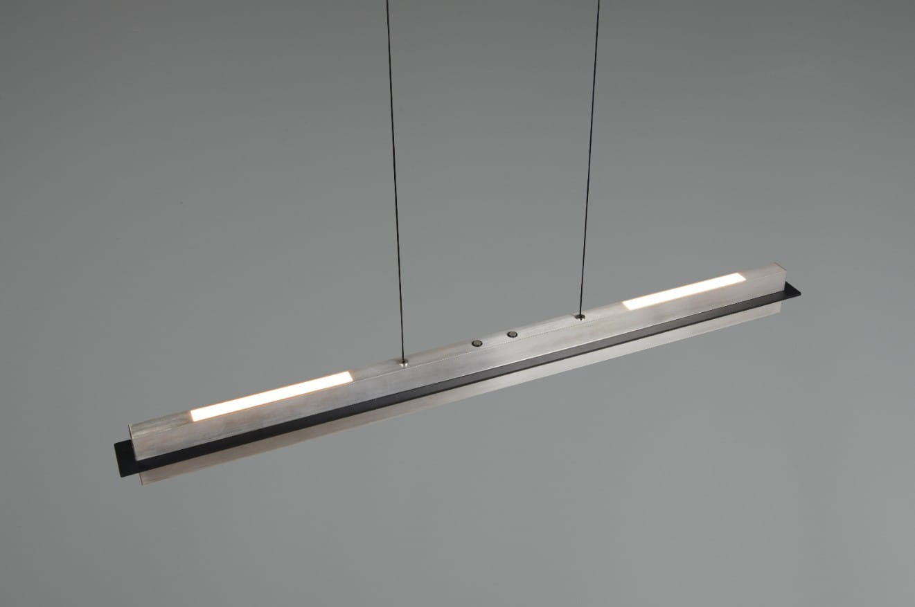 Lampa wisząca Emerson w kolorze niklowym, prostokątna, z jedną żarówką LED 22W. Montowana na dwóch cienkich przewodach, z widocznymi elementami mocującymi. Błyszcząca powierzchnia metalowa, minimalistyczny design, idealna do nowoczesnych wnętrz.