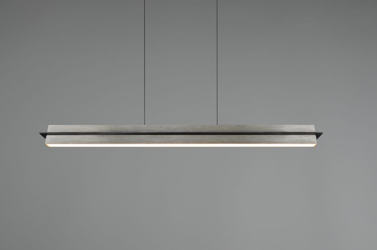 Lampa wisząca Emerson w kolorze niklu, z prostokątnym, metalowym kloszem. Zawieszona na cienkich linkach, z wbudowanym źródłem światła LED o mocy 22W. Minimalistyczny design, idealna do nowoczesnych wnętrz. Tło w jednolitym odcieniu szarości.
