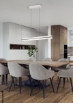 Lampa wisząca Emerson w kolorze szarym z jednolitą, prostokątną oprawą LED na długich linkach, umieszczona nad drewnianym stołem w nowoczesnej jadalni. Tło stanowi jasne wnętrze z szafkami kuchennymi i rośliną dekoracyjną.