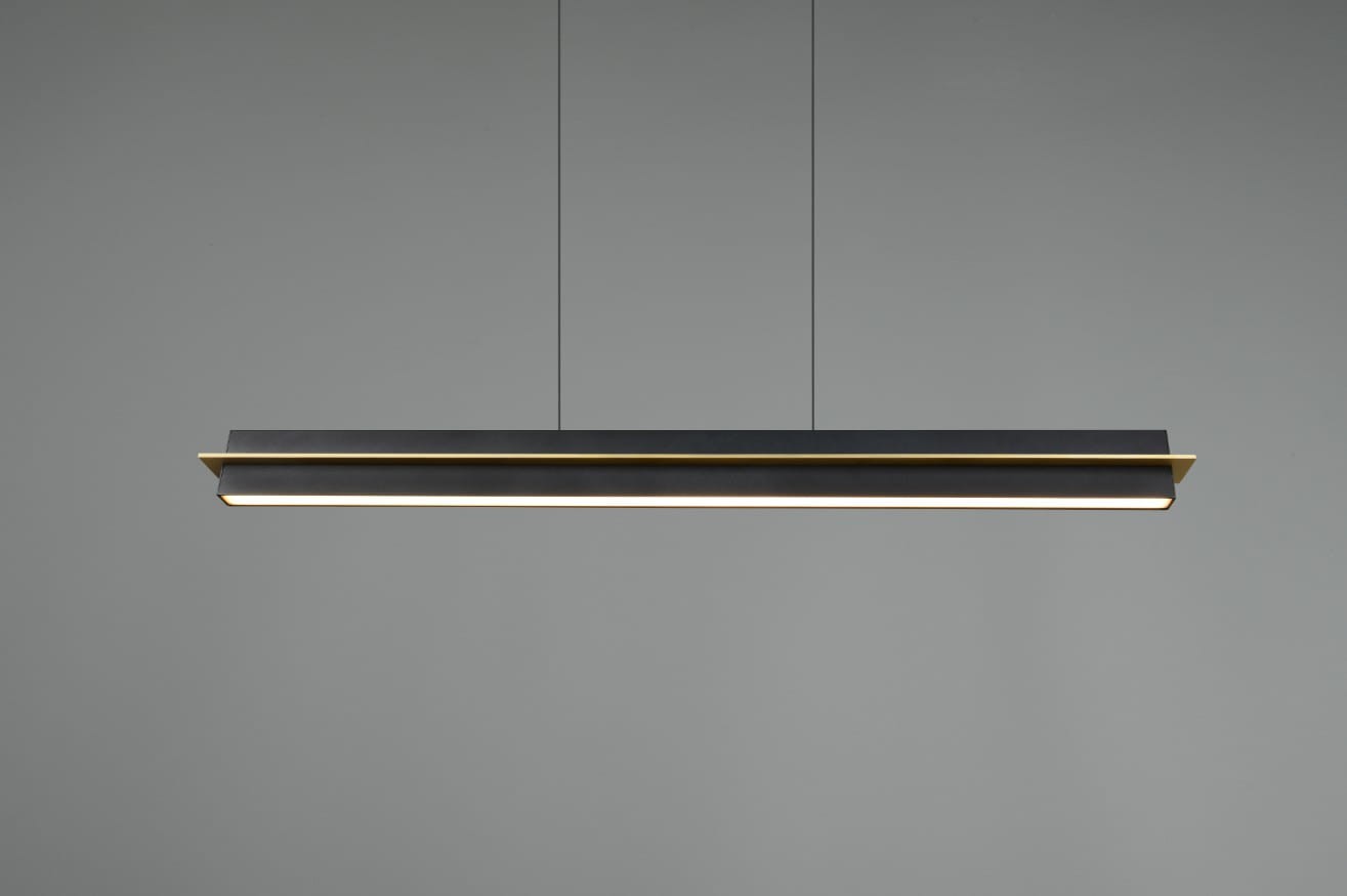 Lampa wisząca Emerson w kolorze czarnym, z jedną diodą LED o mocy 22W. Posiada prostokątny kształt z subtelnym złotym akcentem na krawędzi, zamontowana na cienkich, regulowanych linkach. Tło w odcieniu szarym.