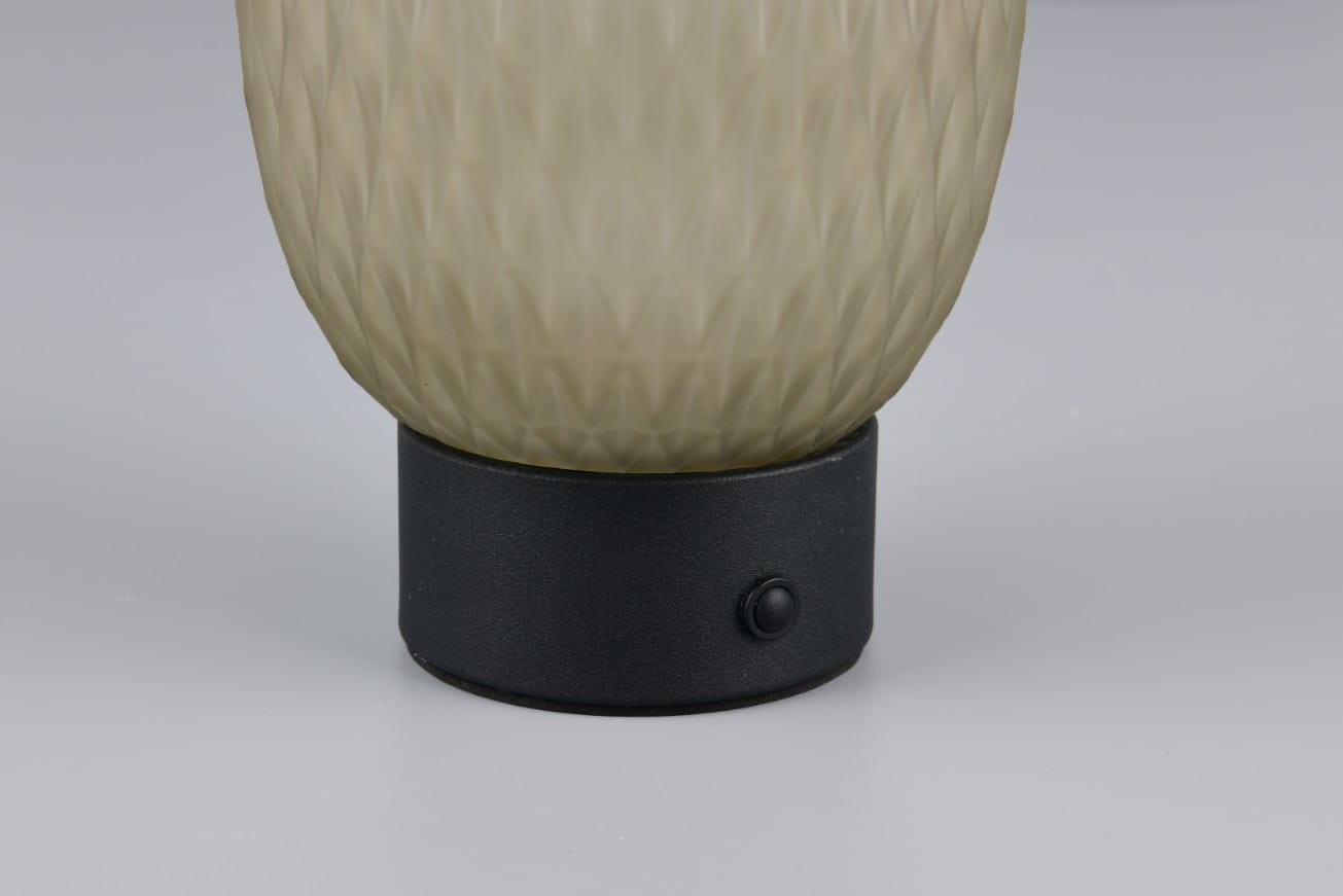 Lampa stołowa Facette w kolorze czarnym i zielonym, z szarym kloszem o teksturze diamentowej. Posiada czarną podstawę z przyciskiem. Widok z boku, ukazujący szczegóły podstawy i klosza.