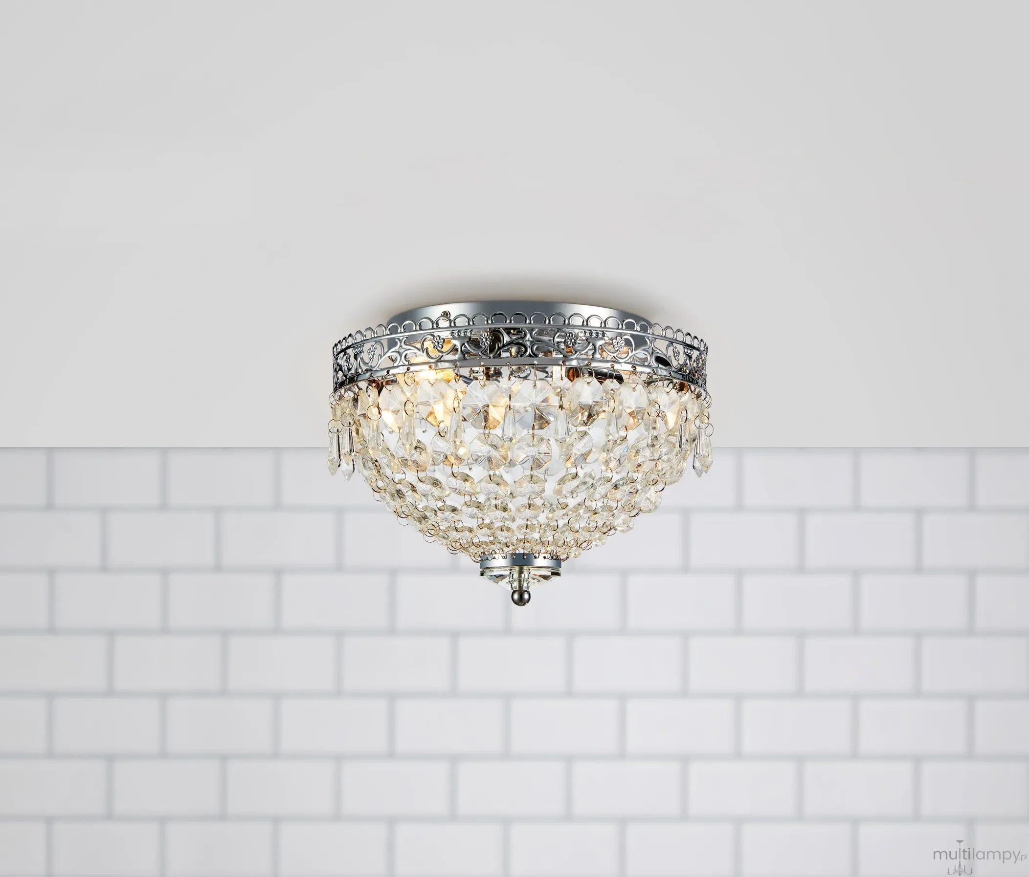 Lampa sufitowa Joline 2-punktowa w chromowanej oprawie, z ozdobnym kloszem pokrytym kryształkami. Ujęcie z dołu, montowana na suficie, w tle jasne płytki ceramiczne. Idealna do nowoczesnych wnętrz.