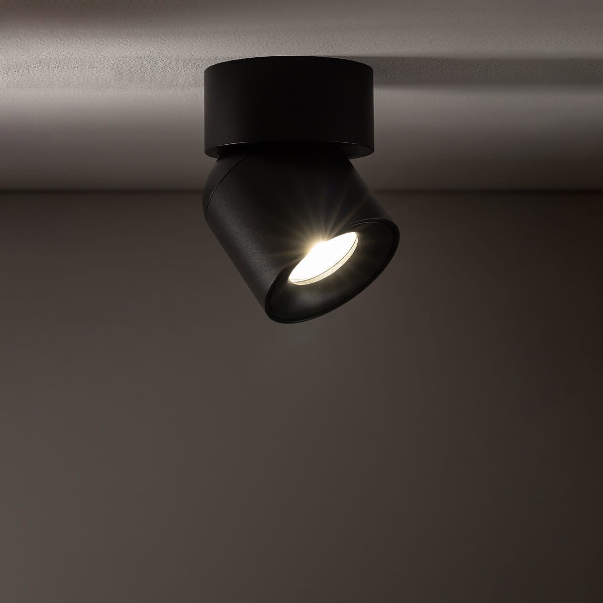 Czarna lampa sufitowa Oscar typu spot, z jedną oprawą na żarówkę GU10, o kształcie cylindrycznym, zamontowana na suficie. Światło emitowane z lampy jest skierowane w dół, podkreślając nowoczesny design. Wysoka klasa szczelności IP54.