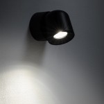 Czarna lampa sufitowa Oscar z pojedynczym spotem GU10, montowana na ścianie. Kąt ujęcia z boku, ukazujący źródło światła i jego efekt na ścianie. Wodoodporna konstrukcja IP54, minimalistyczny design, idealna do wnętrz i na zewnątrz.