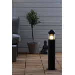 Lampa ogrodowa stojąca Kurt H60 w ciemnoszarym kolorze, o cylindrycznym kształcie, z przezroczystą górą, emitującą światło. Umieszczona na drewnianym tarasie obok doniczki z rośliną oraz figurką Buddy.