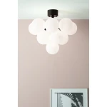 Lampa sufitowa Merlot, 13-punktowa, w kolorze czarnym i białym. Składa się z dużych, matowych kul, zawieszonych na czarnej podstawie. Ujęcie z dołu, na tle różowej ściany, z widocznym fragmentem ramki ze zdjęciem poniżej.