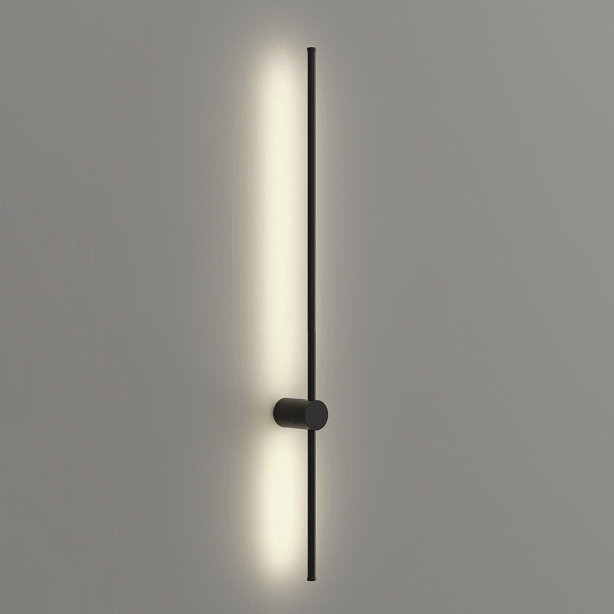 Kinkiet Catrina 90 w kolorze czarnym, zamontowany na ścianie. Składa się z pionowego, cienkiego ramienia z wbudowanym źródłem światła LED o mocy 14W i temperaturze barwowej 4000K, emitującym ciepłe światło. Tło jasnoszare.