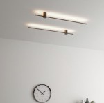 Kinkiet Catrina 120 w kolorze czarnym z jedną diodą LED o mocy 17W i temperaturze barwowej 4000K. Zamontowany na suficie, z minimalistycznym, prostokątnym kształtem oraz subtelnym oświetleniem. W tle widoczny zegar ścienny.