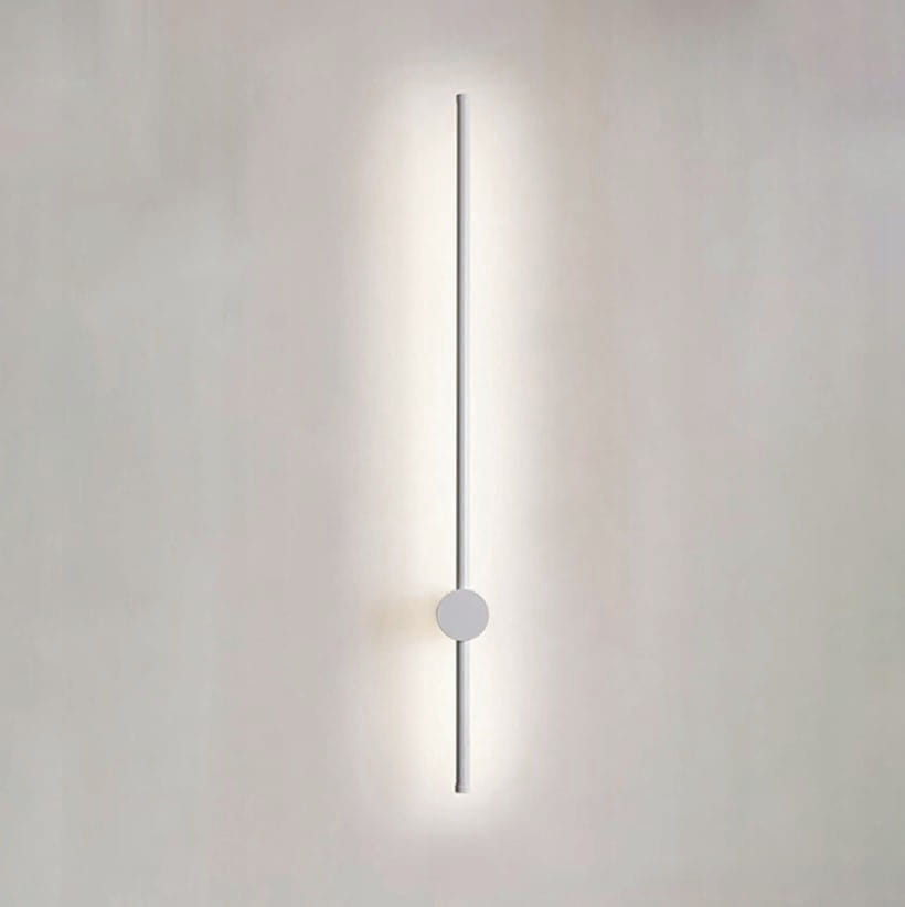 Kinkiet Catrina 90 w kolorze białym, z jedną diodą LED o mocy 14W i temperaturze barwowej 4000K. Produkt o prostym, pionowym kształcie z okrągłym elementem mocującym, zamontowany na jasnym tle.