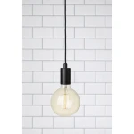 Czarna lampa wisząca Sky z pojedynczym punktem świetlnym. Okrągła, przezroczysta żarówka z widocznymi włóknami, zawieszona na długim czarnym kablu. Tło w jasnym, kafelkowym układzie.