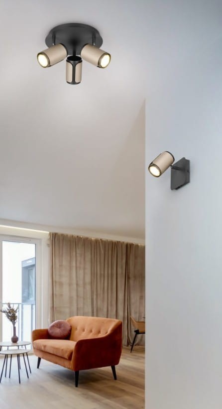 Lampa sufitowa Gillan w kolorze czarnym i kawowym, z trzema ruchomymi reflektorami GU10. Ujęcie z góry, pokazujące lampę zamontowaną na suficie w nowoczesnym wnętrzu z pomarańczową sofą i zasłonami.