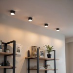 Czarna lampa sufitowa tuba Leto z jednym źródłem światła GX53, zamontowana na suficie. Ujęcie z góry, ukazujące cztery lampy na tle jasnej ściany oraz regałów z książkami i dekoracjami.