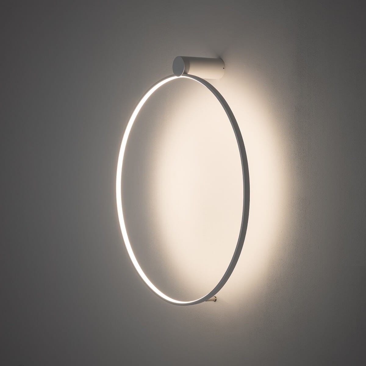 Lampa sufitowa Circolo M w kolorze białym, o okrągłym kształcie, z wbudowanym oświetleniem LED 21W i temperaturze barwowej 3000K. Ujęcie z boku, zamontowana na ścianie, emituje miękkie światło wokół.