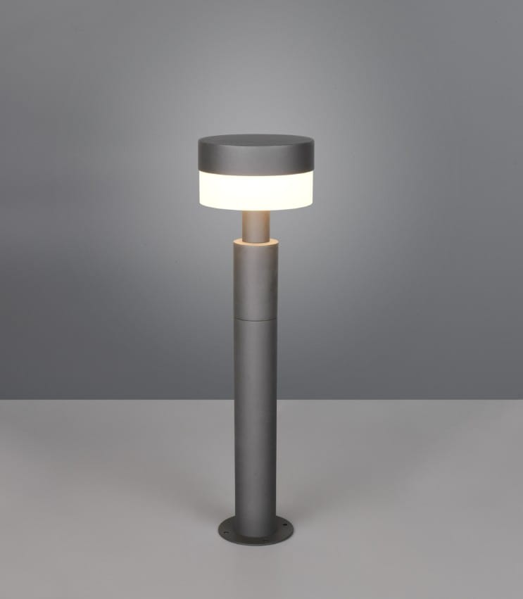 Lampa stojąca ogrodowa Mackenzie H50 w kolorze antracytowym. Posiada okrągłą głowicę z białym kloszem, umieszczoną na cylindrycznym słupku. Wysoka, podstawa montażowa. Wbudowane źródło LED 8W, stopień ochrony IP54. Ujęcie frontalne na jednolitym tle.