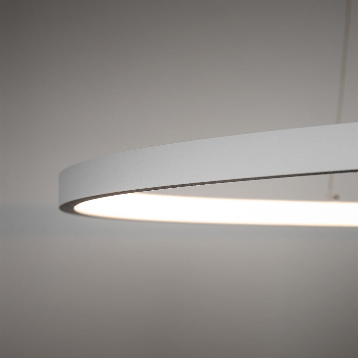 Lampa wisząca Circolo D60 w kolorze białym, wykonana z metalu, o okrągłym kształcie. Widoczna górna krawędź z materiału matowego, z wbudowanym źródłem światła LED o mocy 21W i temperaturze barwowej 3000K. Zawieszona na cienkim przewodzie.