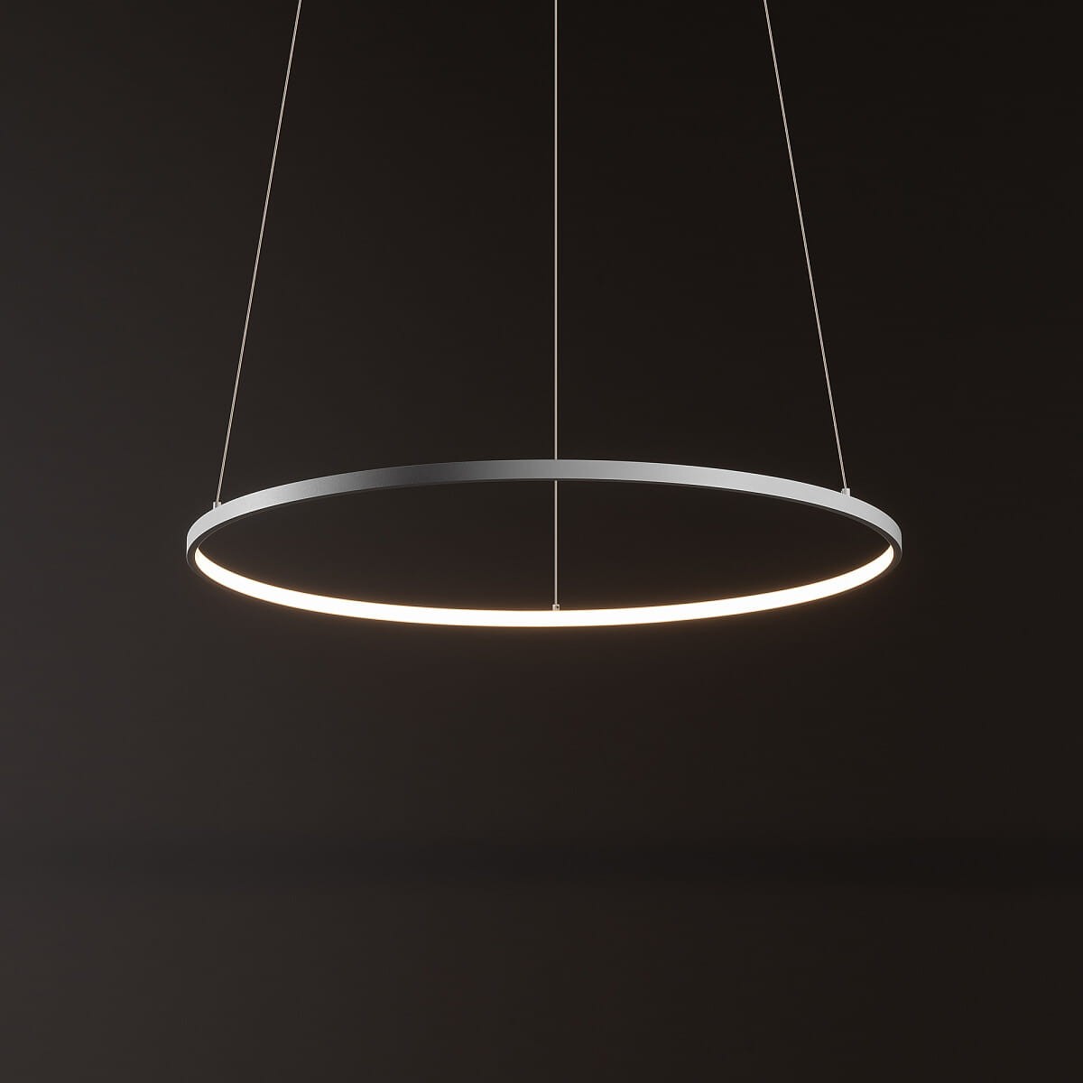 Lampa wisząca Circolo D60 w kolorze białym, okrągła, wykonana z metalu, z zamontowanym źródłem LED o mocy 21W i temperaturze barwowej 3000K. Zawieszona na cienkich linkach, w minimalistycznym stylu, na ciemnym tle.