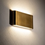 Mosiężny kinkiet elewacyjny Semi M, z dwoma diodami LED, o mocy 10W i temperaturze barwowej 3000K. Zainstalowany na ścianie, emituje ciepłe światło, podkreślając teksturę tła. Kształt prostokątny z zaokrąglonymi krawędziami, matowe wykończenie.