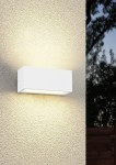 Kinkiet zewnętrzny Mayenne 2xE14 w kolorze białym, prostokątny, zamontowany na ścianie. Emituje światło w górę i w dół, na tle strukturalnej, jasnej powierzchni. Idealny do oświetlenia elewacji budynków.
