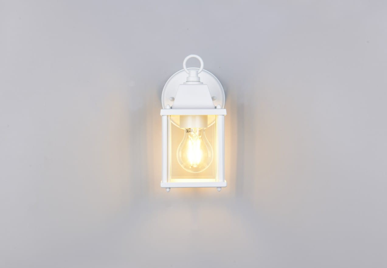 Biały kinkiet zewnętrzny Mirande z oprawą w formie lampionu, z widoczną żarówką E27. Ujęcie frontalne, produkt zamontowany na ścianie, z prostą, elegancką konstrukcją. Tło szare, co podkreśla jasność lampy.