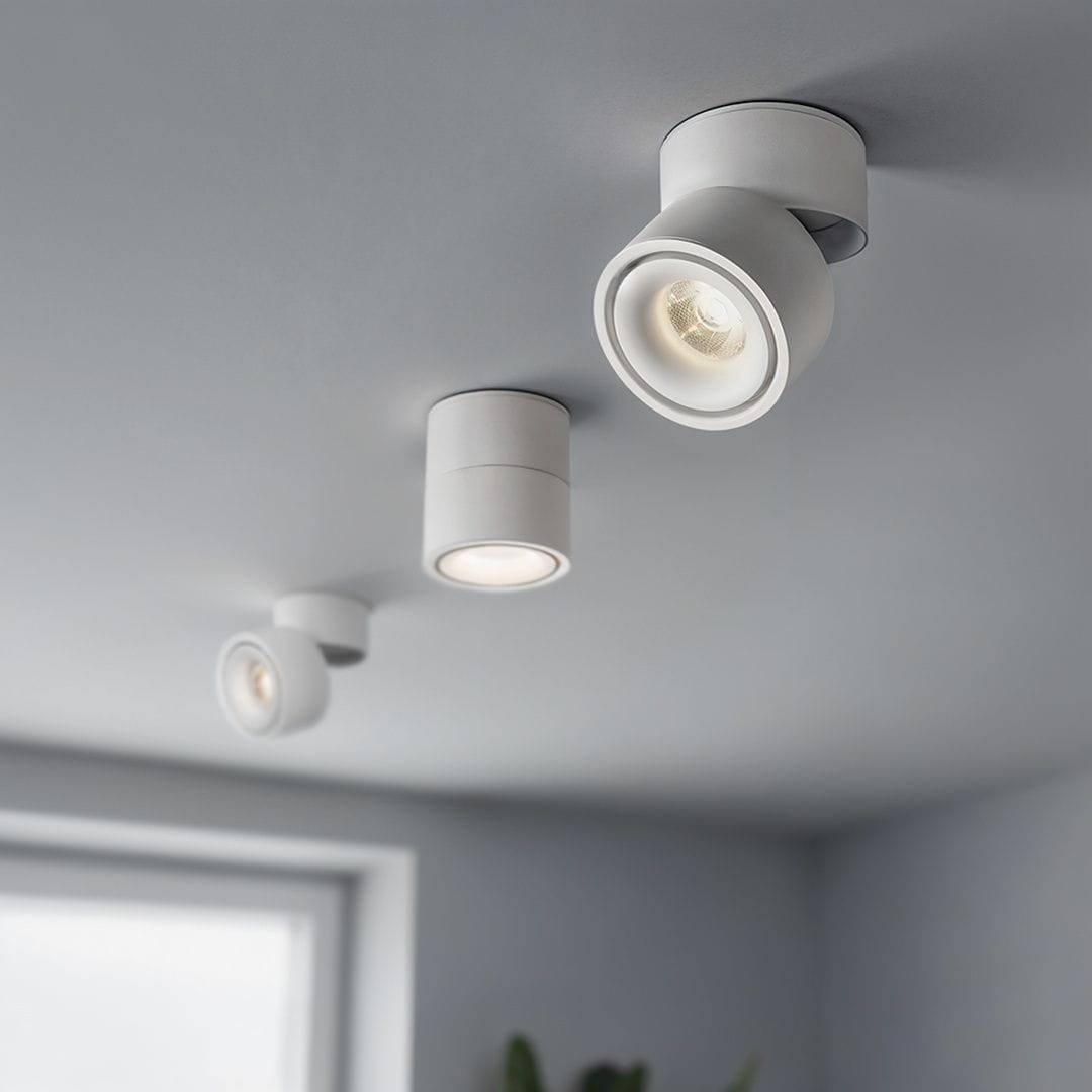 Biała lampa sufitowa Tubo z trzema spotami LED, każdy o mocy 12W i temperaturze barwowej 4000K. Ujęcie z góry pokazuje lampy zamontowane na suficie, w różnych pozycjach, z widocznymi zaokrąglonymi kloszami. Tło w jasnym kolorze.