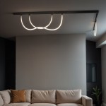 Wężyk LED 150 do szyny magnetycznej, o mocy 12W i barwie światła 3000K. Wyglądająca jak płynna linia, zamontowana na ciemnym stropie, oświetla przestrzeń nad jasną sofą w nowoczesnym wnętrzu.