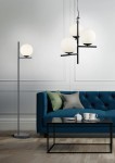 Czarna lampa wisząca Pure z trzema okrągłymi, matowymi kloszami, zawieszona na cienkim kabelku. Produkt umieszczony w nowoczesnym wnętrzu z niebieską kanapą i czarnym stołem, na którym znajdują się filiżanki.