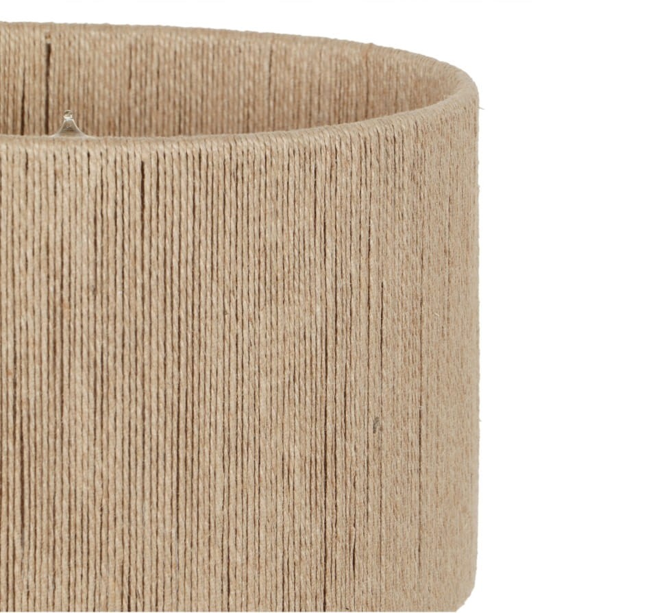 Lampa stojąca Toba z abażurem z juty w jasnym odcieniu, o cylindrycznym kształcie, z widoczną teksturą materiału. Ujęcie zbliżeniowe na detal abażuru, pokazujące jego plecionkę. Przeznaczona na żarówkę E27.