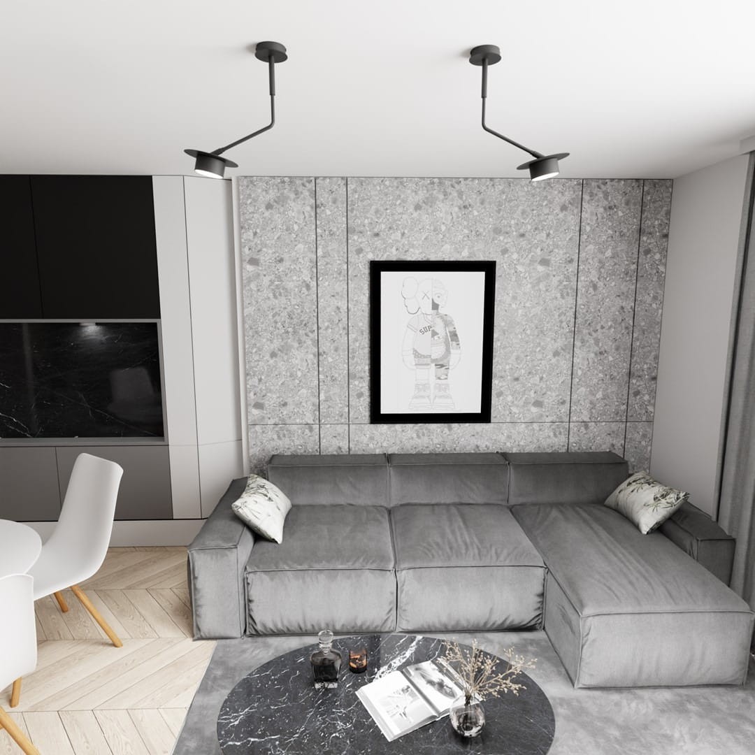 Czarna lampa sufitowa Mizu 1xGX53 z regulowanym ramieniem, montowana na suficie. Zawieszona w nowoczesnym wnętrzu, obok szarej sofy i okrągłego stolika. Tło w odcieniach szarości, minimalistyczny design.