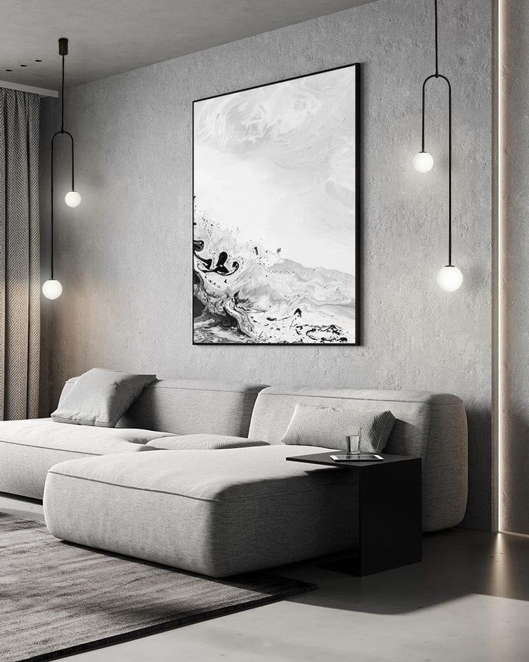 Czarna lampa wisząca 2-punktowa z okrągłymi kloszami, zawieszona w nowoczesnym wnętrzu. Lampa umieszczona nad szarym narożnikiem, na tle betonowej ściany i obrazu. Długa, cienka konstrukcja z minimalistycznym designem.
