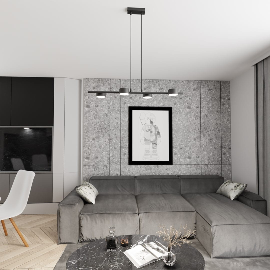 Lampa wisząca Sora w kolorze czarnym, z czterema źródłami światła GX53, zamontowana na prostokątnym stelażu. Widoczna w nowoczesnym wnętrzu, nad szarym narożnikiem i okrągłym stolikiem, na tle szarej, strukturalnej ściany z ramką obrazu.