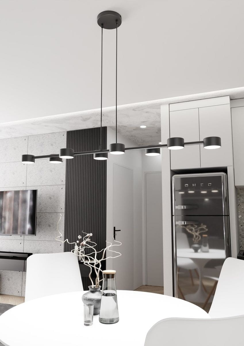 Lampa wisząca Megara w kolorze czarnym, z ośmioma oprawami GX53. Zawieszona na długich przewodach, umieszczona nad stołem w nowoczesnej kuchni. W tle widoczna szara ściana i sprzęt AGD.