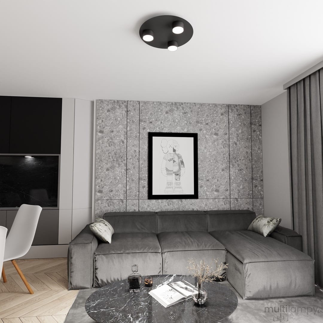 Czarna lampa sufitowa Bolx z trzema źródłami światła typu GX53, zamontowana na suficie w nowoczesnym wnętrzu. Widoczna w aranżacji z szarym narożnikiem, marmurowym stołem oraz dekoracjami na tle szarej ściany.