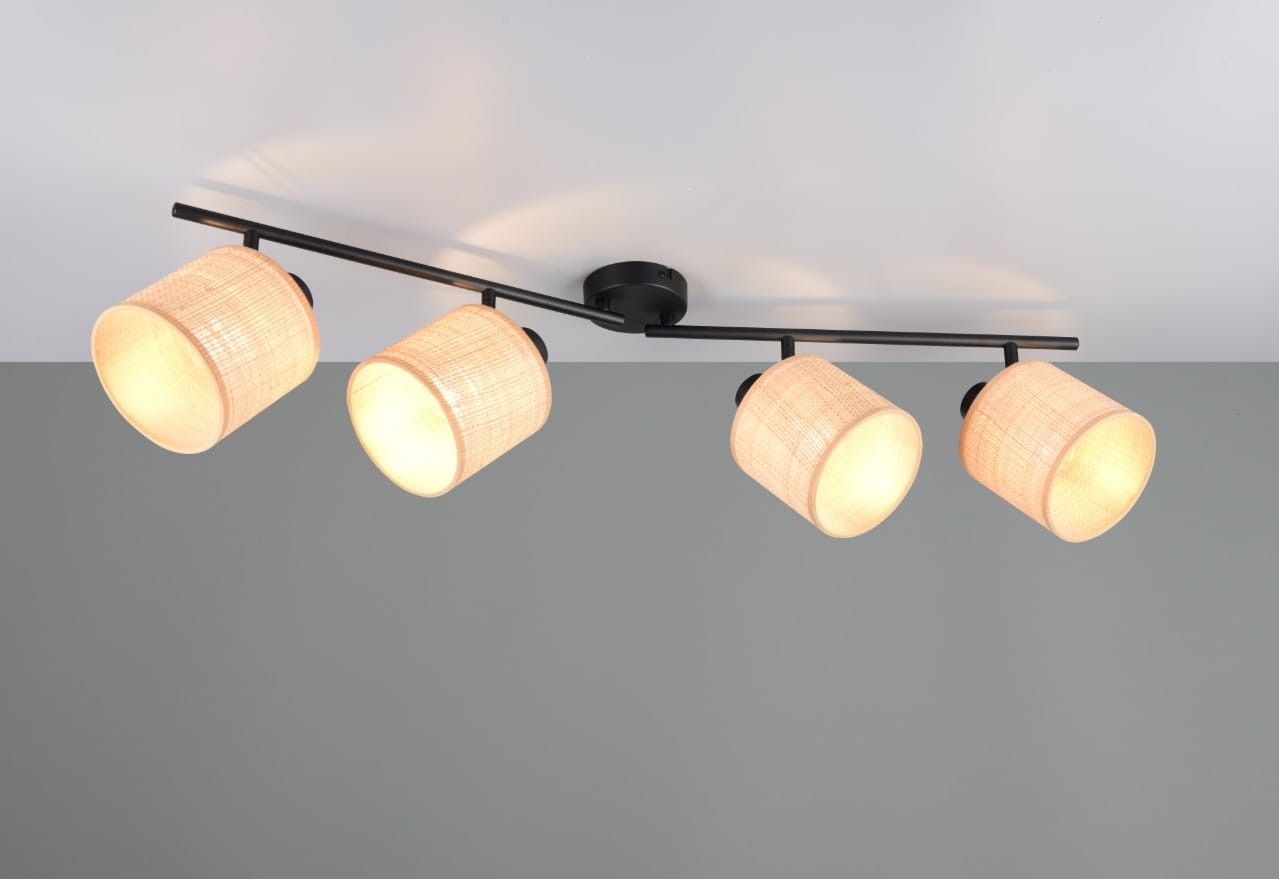 Czarna lampa sufitowa Aimee z czterema reflektorami E14, w naturalnych kloszach z plecionki. Ułożona na czarnej metalowej belce, zamontowana na suficie. Klosze emitują ciepłe światło, tworząc przytulną atmosferę.