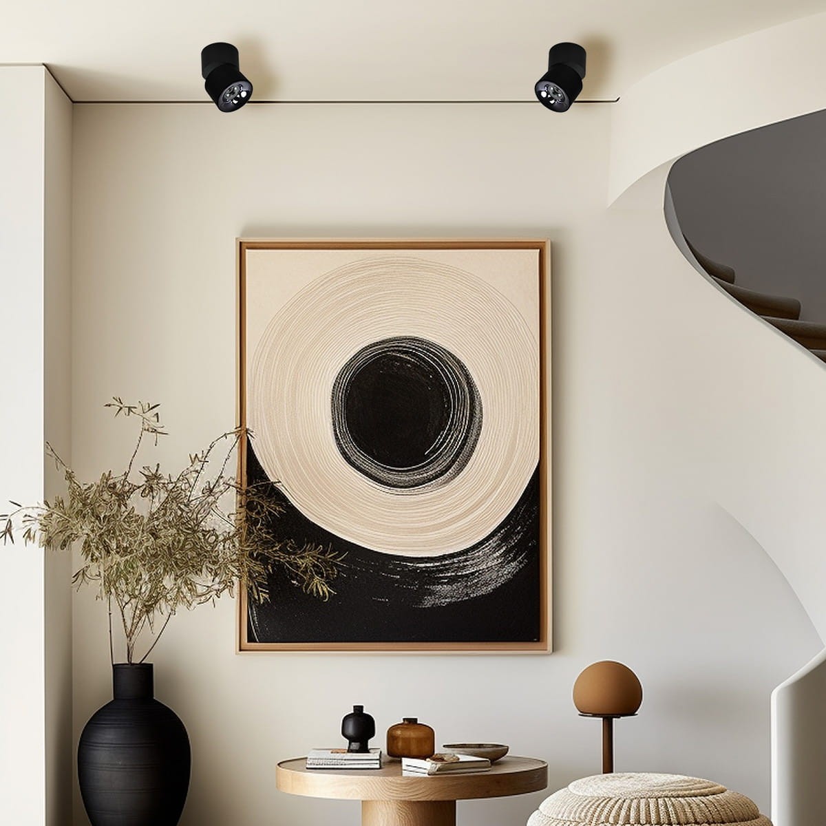 Czarna lampa sufitowa Brema (spot) z jedną żarówką LED 10W, umieszczona na suficie, z możliwością regulacji kierunku światła. W tle widoczny nowoczesny obraz oraz elementy dekoracyjne na stole.